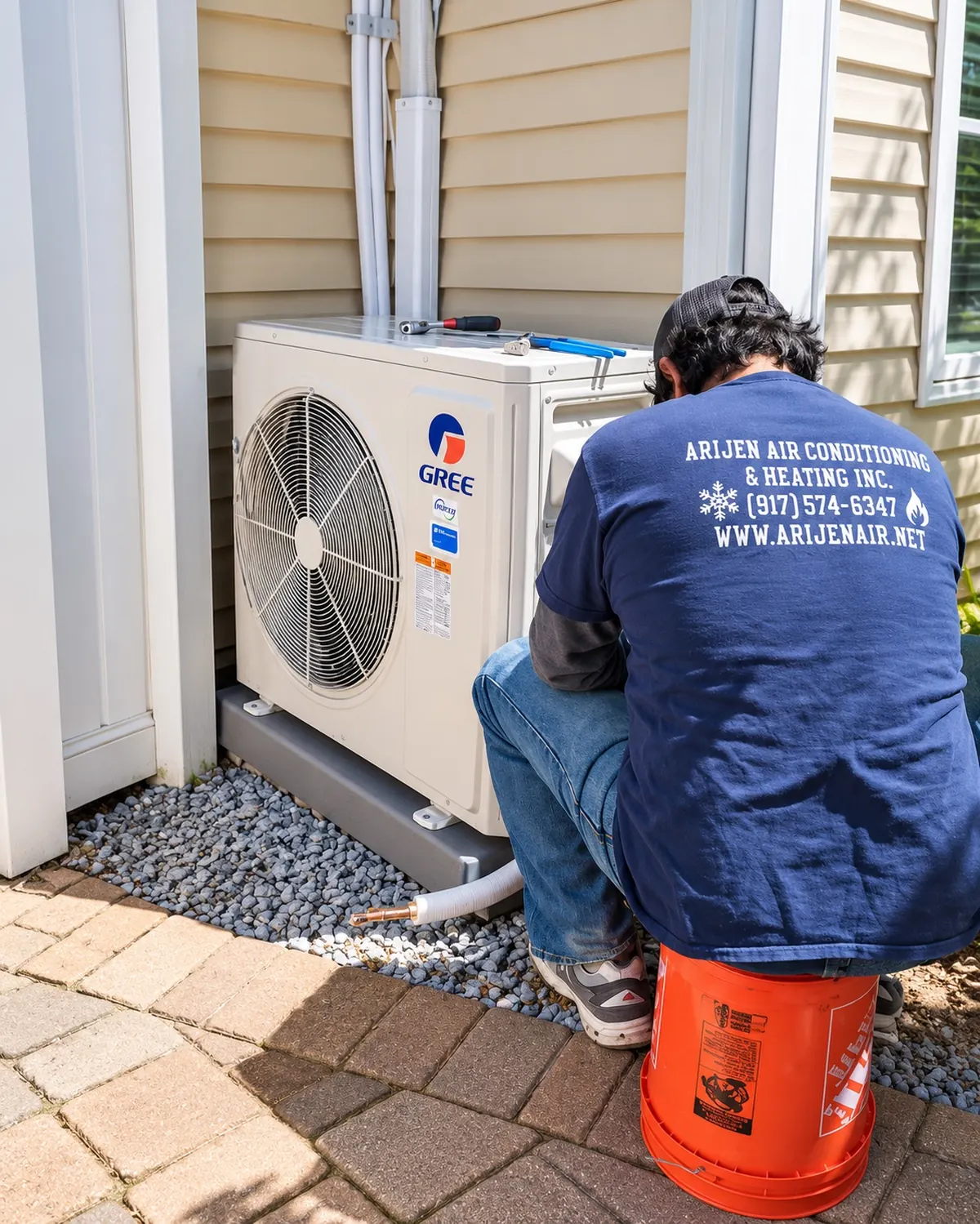 Arijen technician seen from behind in a company shirt, servicing a Gree ductless outdoor unit